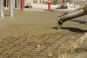 Workers pouring a concrete pad outside a new commercial building.